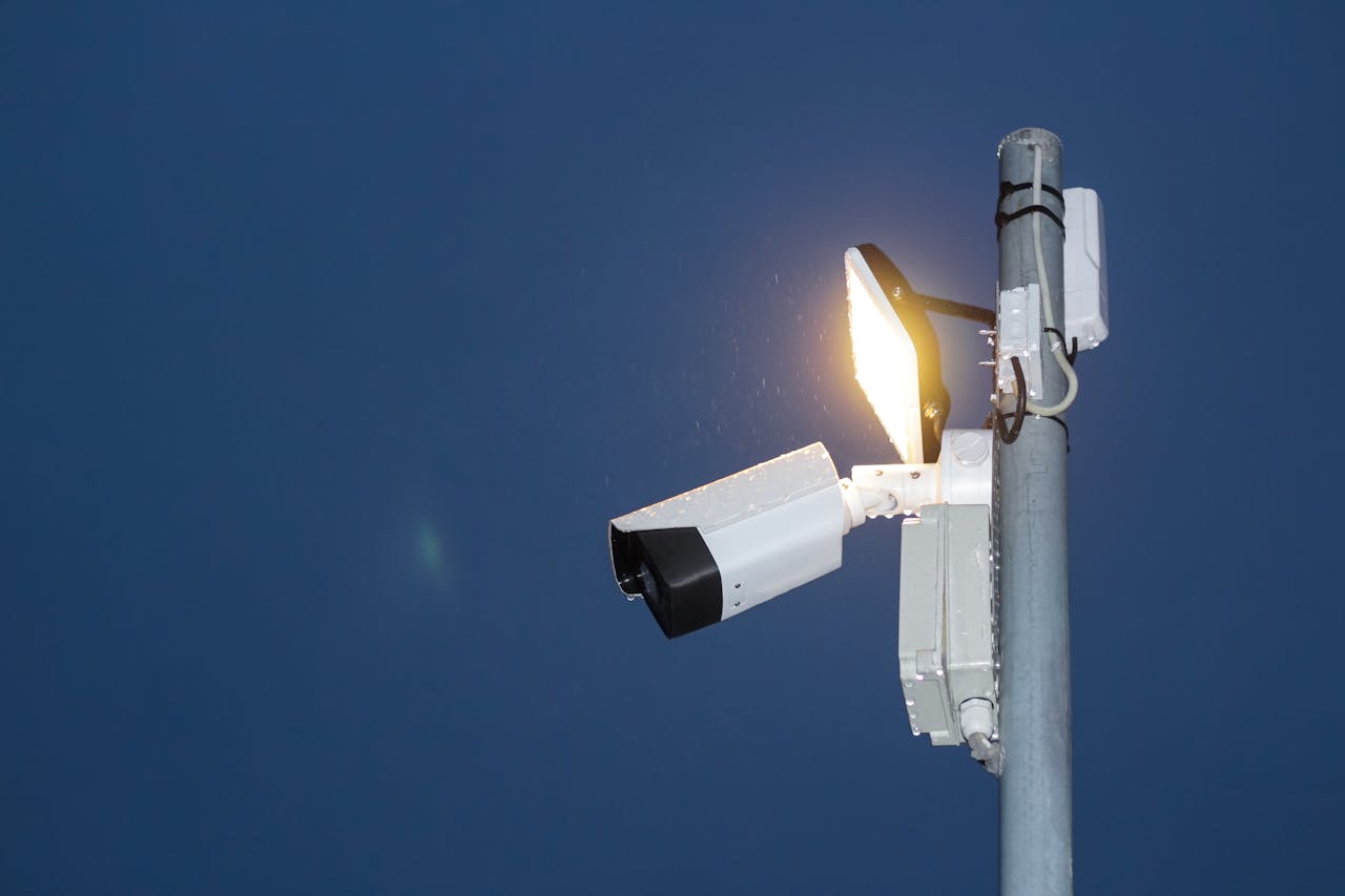gallery-4 Low angle view of a security camera and light against a dark blue night sky.